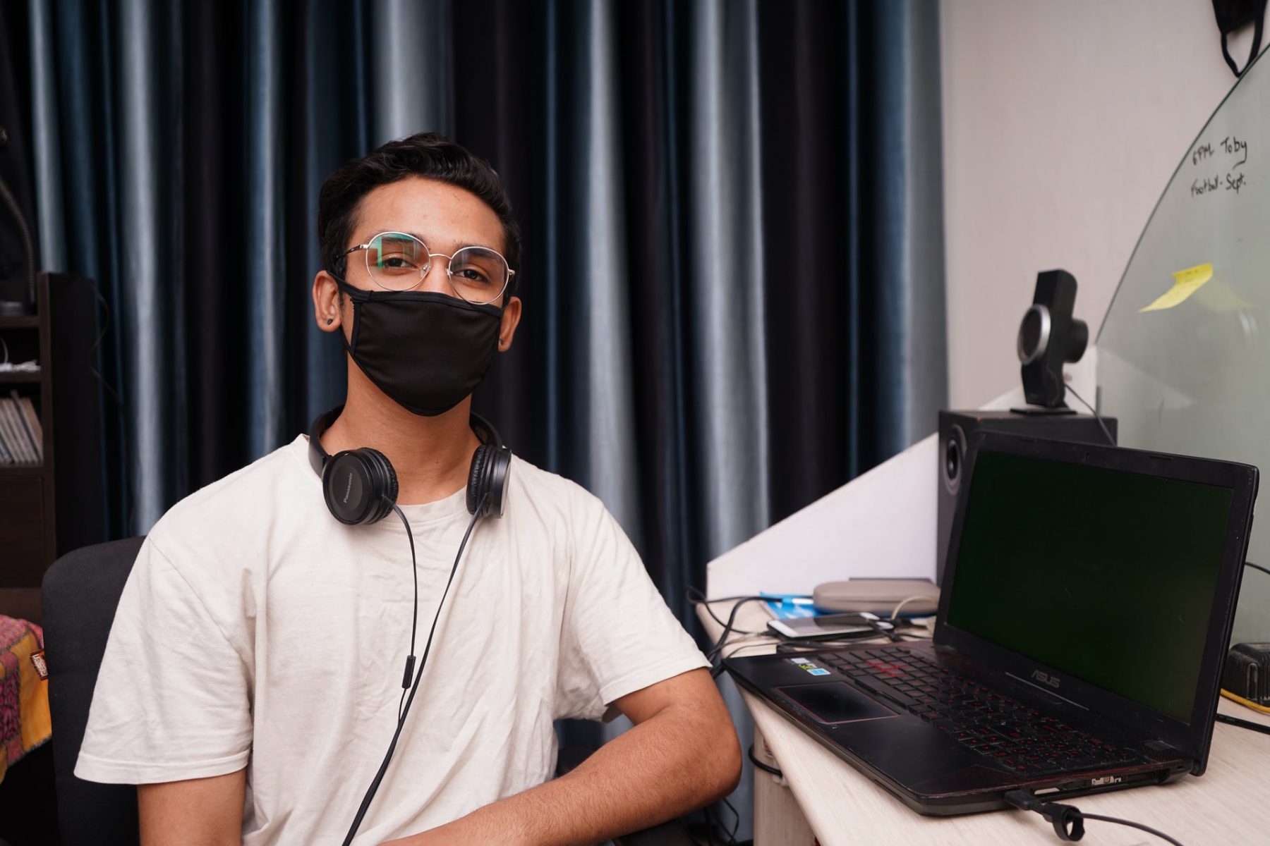 man in headphones and face mask sitting near a computer